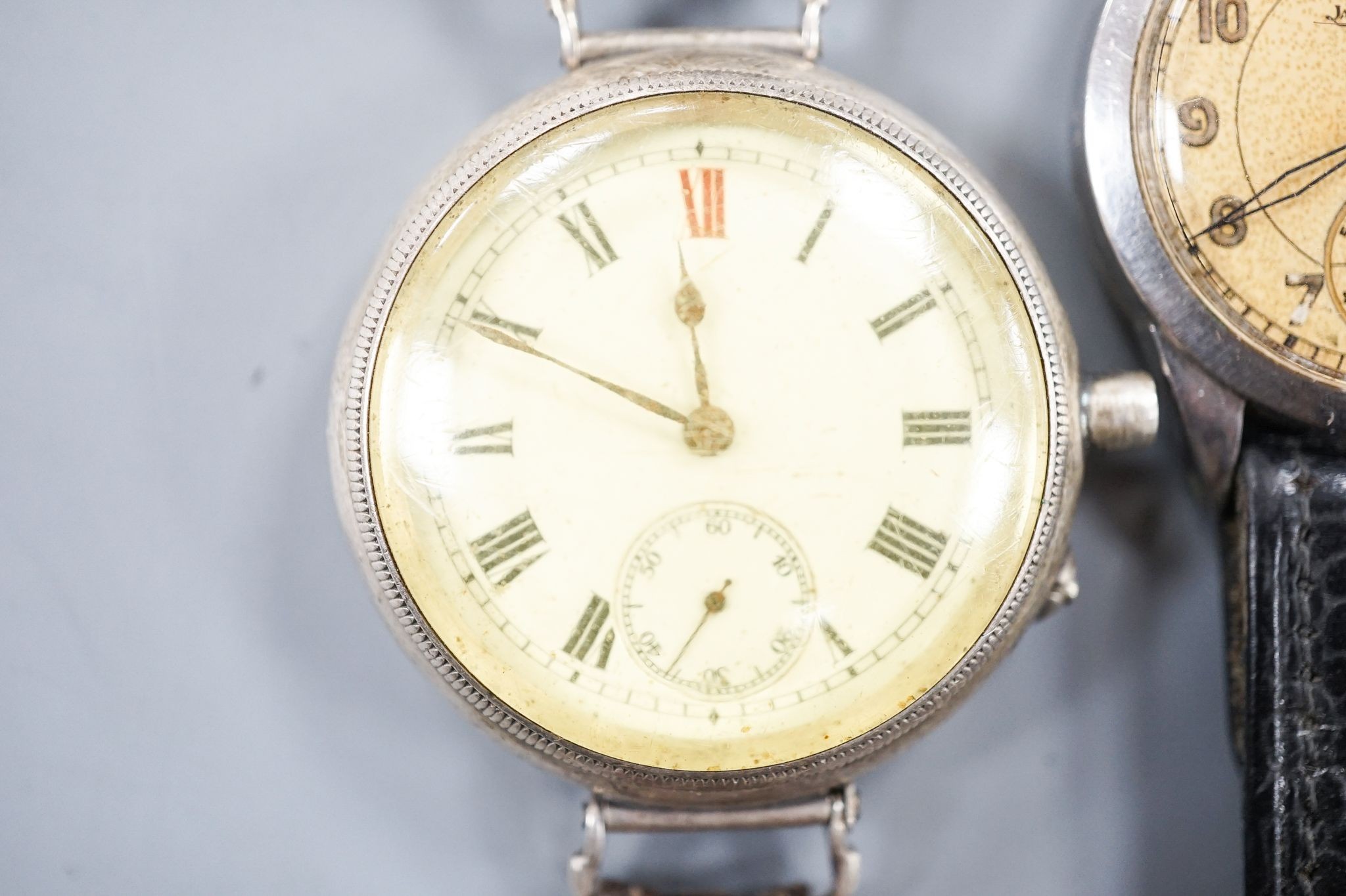 A gentleman's stainless steel Jaeger LeCoultre manual wind wrist watch, case back numbered 64765, on associated strap and a white metal fob watch, now mounted as a wrist watch(a.f.).